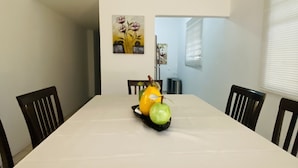 Una mesa de comedor con mantel blanco, rodeada por cuatro sillas.