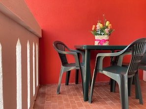 Un mur rouge, une table avec des chaises et un bouquet de fleurs.