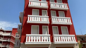 Un edificio rojo con balcones blancos y numerosas ventanas.