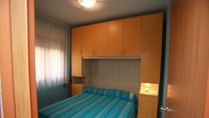 Un dormitorio con cama, armarios de madera, una mesita de noche y una lámpara.