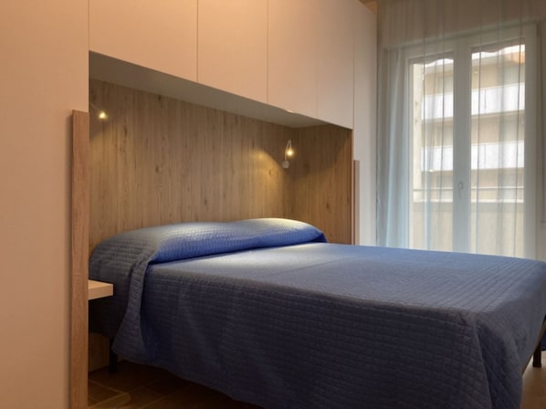 Ein Schlafzimmer mit einem Bett, einem Holzkopfende und einem Fenster mit Vorhängen.