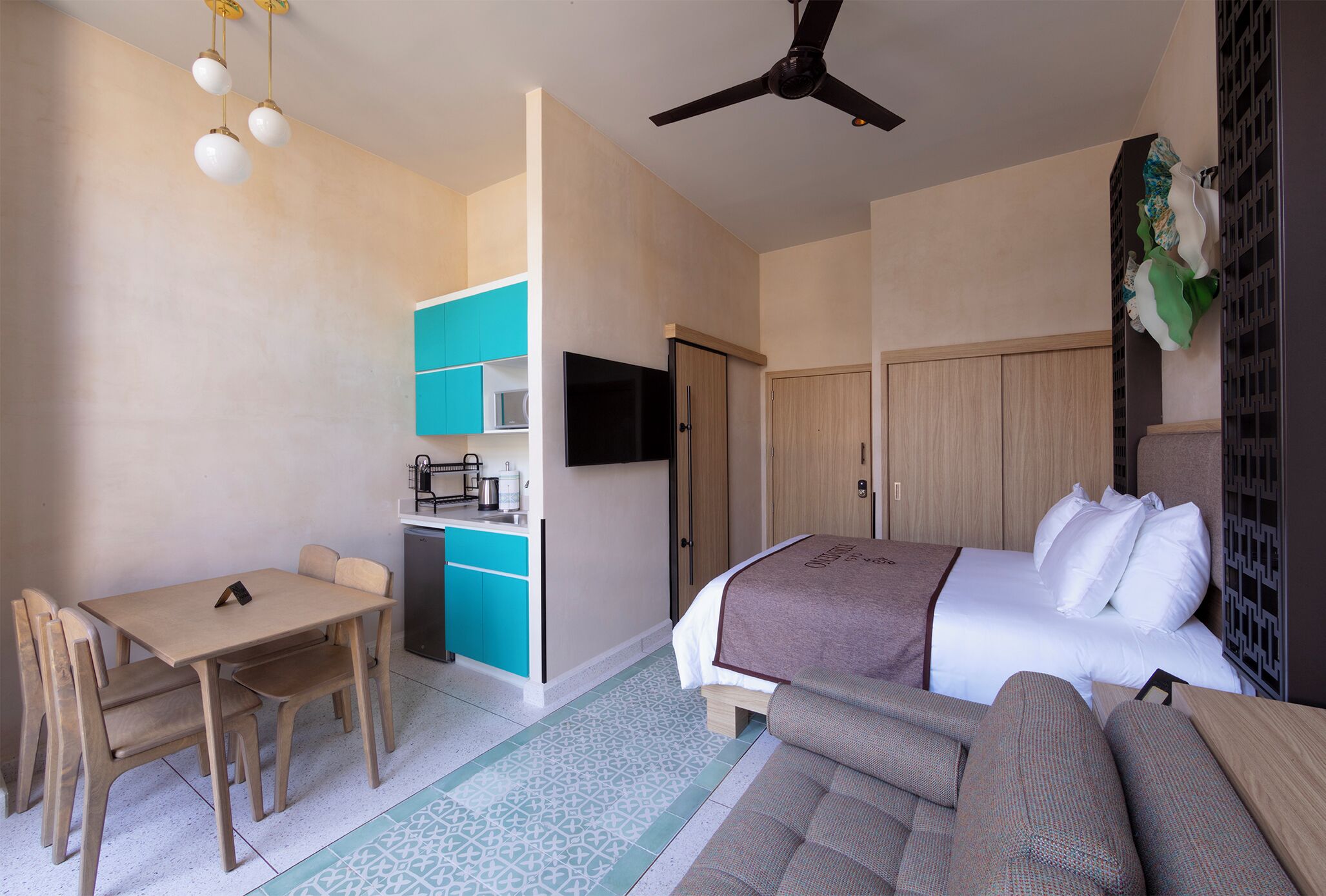 Une chambre d’hôtel compacte comprenant un lit, un canapé, une petite table à manger et une kitchenette.