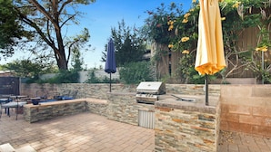 Terrassa exterior amb una barbacoa, zona de seients i ombrelles.