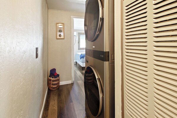 A laundry room with two stacked washers and dryers, a wooden floor, and a hallway leading to a bedroom. - Cozy Sedona Hideaway w/ deck, firepit & walking distance to trails & restaurants (Sedona)