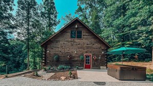 A log cabin with a red door, surrounded by a gravel driveway and a small garden. - Rustic Oak Cabin - dogs welcome - Hocking hills (Logan)