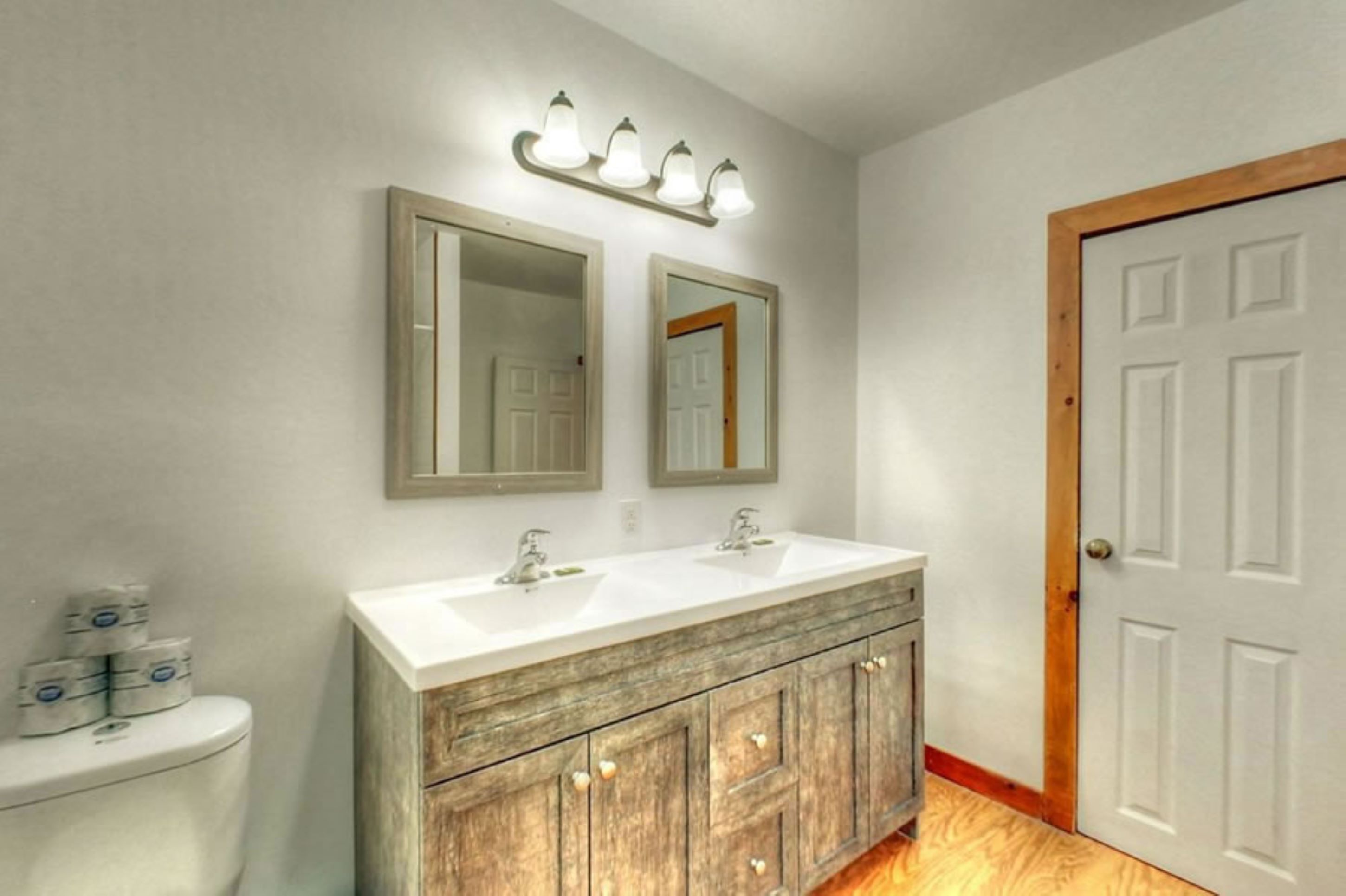 Une salle de bain avec deux lavabos, un meuble-lavabo en bois et une porte blanche.