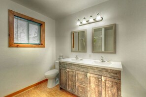 A bathroom with a wooden vanity, two mirrors, a toilet, and a window with blinds. - Spacious 8 bdrm Cottage with Private Beach Access, BBQ, Hot Tub, Sauna, Pet friendly (The Blue Mountains)