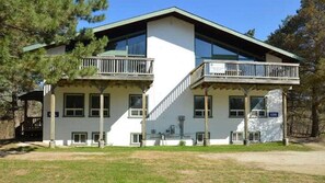 A two-story building with a balcony on the upper floor, a covered porch on the ground floor, and a clear sky in the background. - Spacious 8 bdrm Cottage with Private Beach Access, BBQ, Hot Tub, Sauna, Pet friendly (The Blue Mountains)