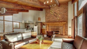 A spacious living room with a fireplace, leather sofas, and a wooden coffee table. - Spacious 8 bdrm Cottage with Private Beach Access, BBQ, Hot Tub, Sauna, Pet friendly (The Blue Mountains)