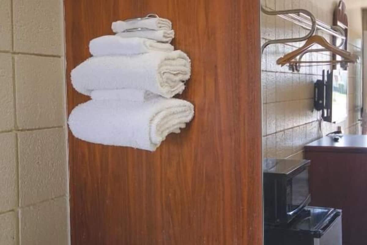 A bathroom with a wooden door, a mirror, and a stack of white towels.