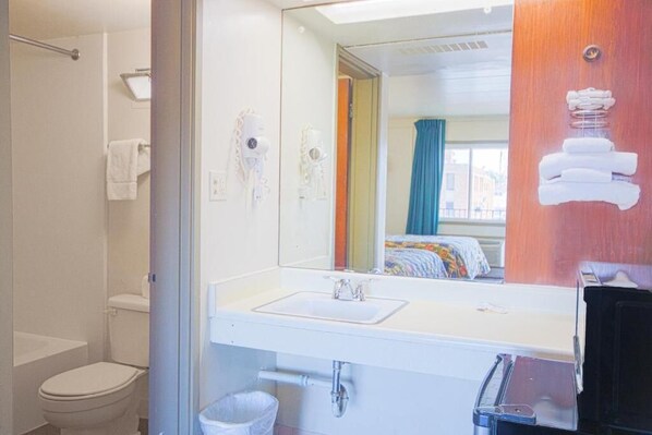 A bathroom with a white sink, a mirror, a towel rack, and a shower area. - centralia motel (Centralia)
