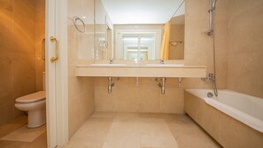 Une salle de bain moderne avec une douche à l’italienne, des toilettes et une baignoire.