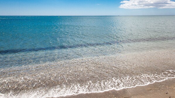 Une plage avec une eau claire et peu profonde et un rivage sablonneux.