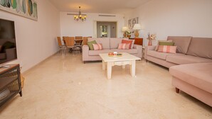 Un salon comprenant un canapé, une table basse, un téléviseur et un coin repas avec des chaises et une table.
