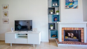 A modern living room with a flat-screen TV, white entertainment unit, and a fireplace with a brick surround. - Manilva Gardens F A2 (Manilva)