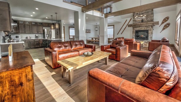 A spacious living area with leather sofas, a wooden coffee table, and a fireplace. - Brand New 7 bdrm Luxury Cottage with Private Beach Access, BBQ,7.5 baths, Hot Tub, Ping Pong Table (The Blue Mountains)