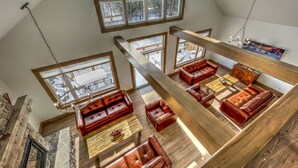 A spacious loft-style living area with high ceilings, large windows, and a wooden staircase. - Brand New 7 bdrm Luxury Cottage with Private Beach Access, BBQ,7.5 baths, Hot Tub, Ping Pong Table (The Blue Mountains)