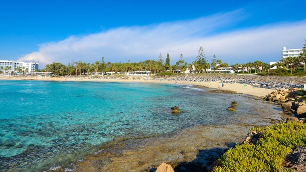 Een strandresort met helder turquoise water, zandstranden en palmbomen.