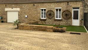 Un bâtiment en pierre avec une porte de garage blanche, deux fenêtres dotées de volets en bois et une porte avec un panneau de verre.