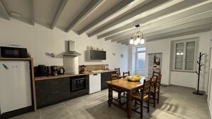 Une cuisine moderne avec un coin repas, comprenant une table et des chaises en bois, un four encastré et un four à micro-ondes.