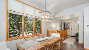 A dining area with a wooden table, chairs, and a hanging light fixture. - AC! 2 Kings 2 Twins Condo - Walk to River! Close to downtown and RMNP (Estes Park)