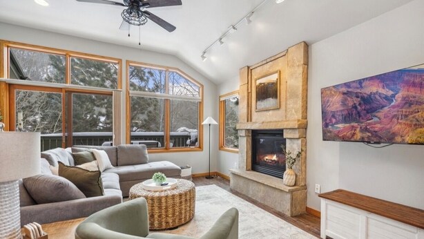 A spacious living room with a fireplace, large windows, and a mountain painting. - AC! 2 Kings 2 Twins Condo - Walk to River! Close to downtown and RMNP (Estes Park)