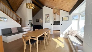 A modern kitchen with a wooden table and chairs, a built-in oven, and a large window providing natural light. - Sunset Sanctuary - Havelock North Holiday Home (Havelock North)