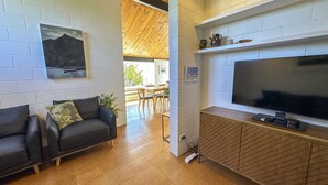 A modern living room with a sofa, TV, and a dining area with chairs and a table. - Sunset Sanctuary - Havelock North Holiday Home (Havelock North)