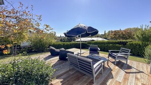 A wooden deck with outdoor furniture, including a table and chairs, and a large umbrella providing shade. - Sunset Sanctuary - Havelock North Holiday Home (Havelock North)