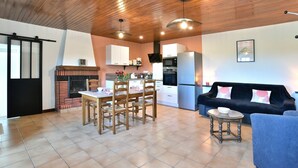 Une cuisine moderne avec un coin repas, un plafond en bois et un canapé noir.