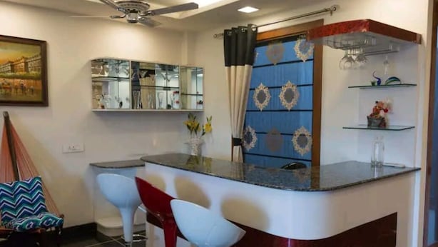 A modern kitchen with a bar area, a ceiling fan, and a decorative mirror. - The place is very much pleasing , adorable and comfortable . Also amazing decor  (Delhi)