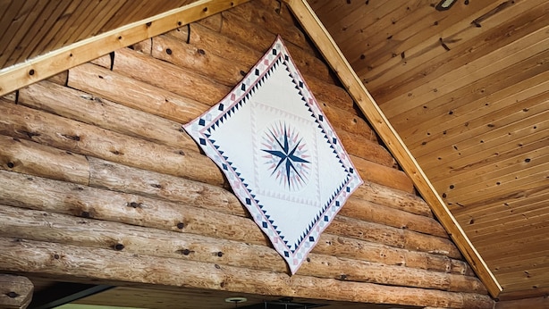 A log cabin interior with a dining area, a sofa, and a patterned rug. - Log Cabin Haus, Amish Country. 
Shipshewana, Indiana near Pumpkinvine Trail (Shipshewana)