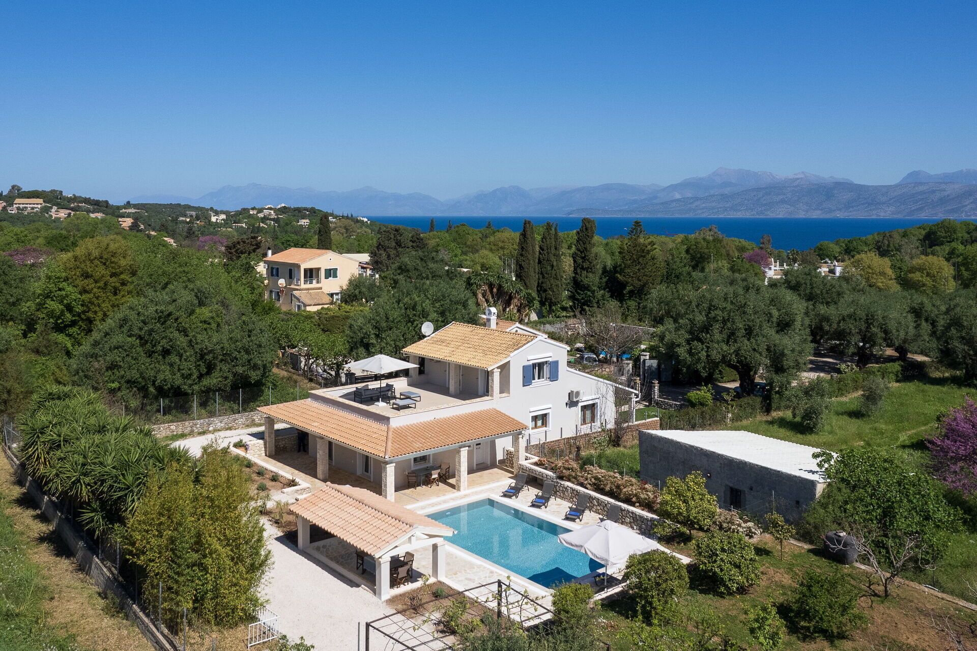 Eine Villa mit Swimmingpool, mehreren Terrassen und Meer- und Bergblick.