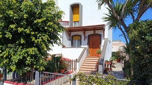A white building with a red-tiled roof, a wooden door, and a staircase leading to the entrance. - Marleneee! (Torre a Mare)