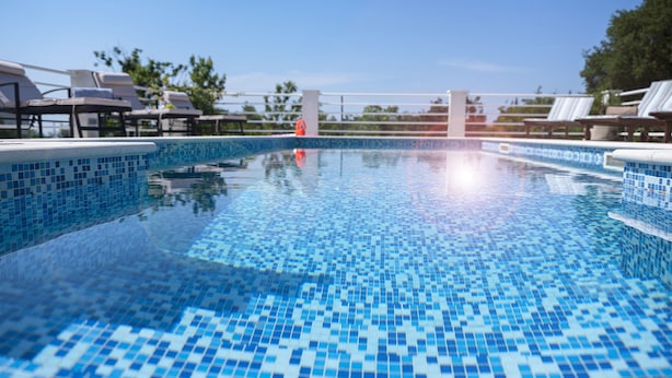A clear blue pool with tiled edges, surrounded by lounge chairs and umbrellas, indicating a resort setting. - Villa Oliva Beautiful Magnificent View, Pool, Newly Built, Close to the Beach (Zaton)