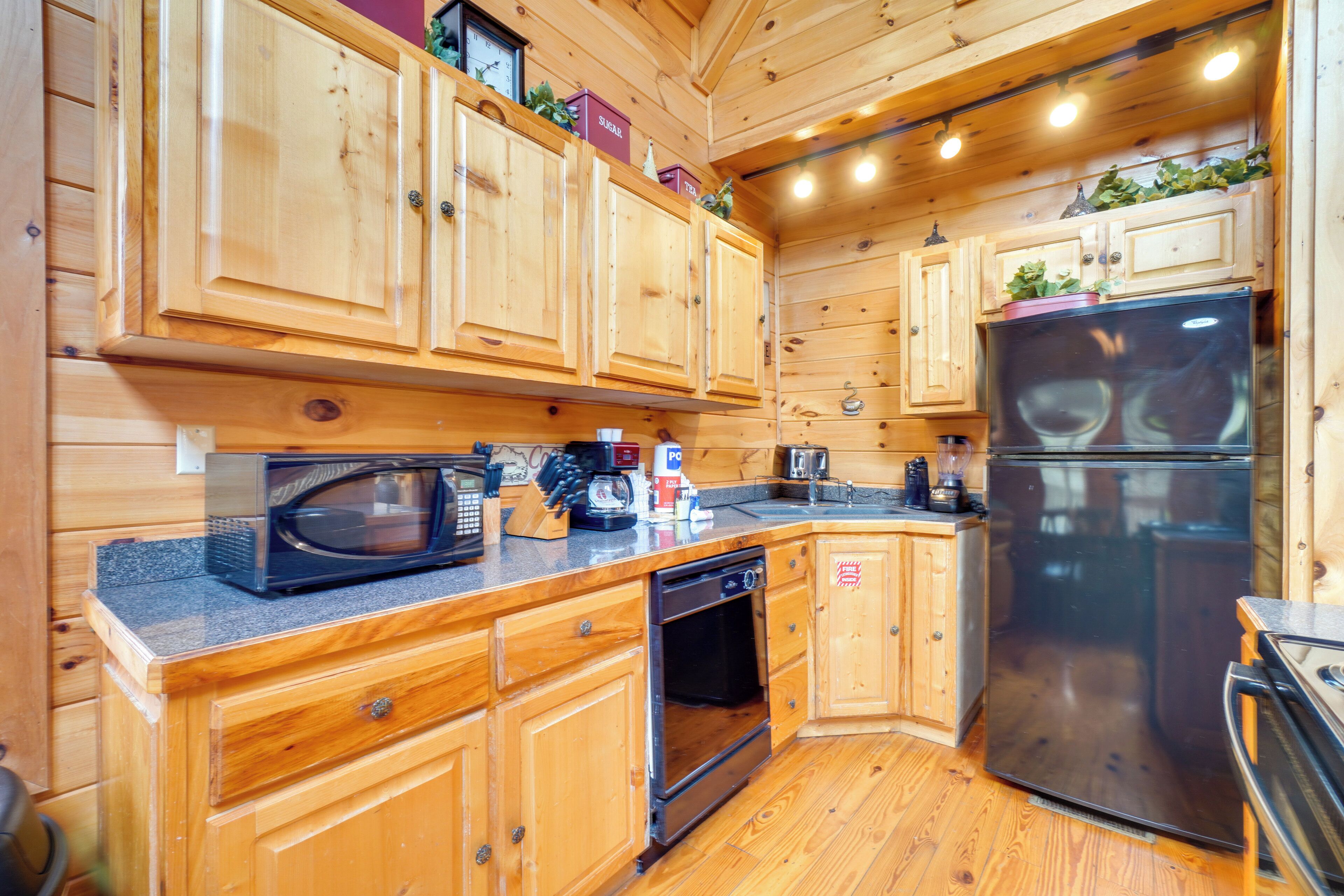 Una cocina tipo cabaña de madera, con armarios de madera, microondas, refrigerador y lavavajillas.