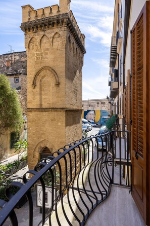 Un stretto vicolo con una torre in pietra, una ringhiera in metallo e un murale su un edificio.