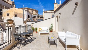 A balcony with a white sofa, a small table, and a chair. - Sette Fate Suites and Spa (Palermo)