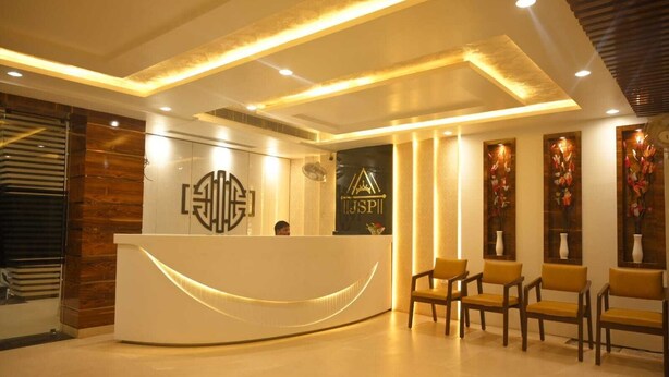 A reception area with a modern design, featuring a curved reception desk, a logo, and a seating area with chairs. - Hotel Jatashankar Palace (Chhatarpur)