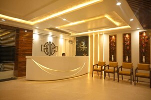 A reception area with a modern design, featuring a curved reception desk, a logo, and a seating area with chairs.