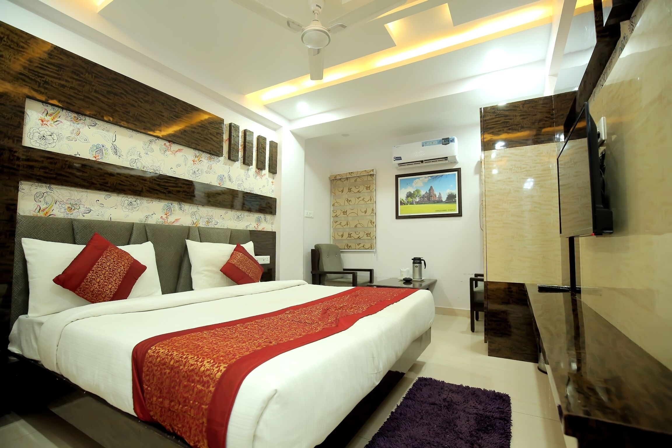 Quarto de hotel moderno com uma cama grande, televisão de tela plana, escrivaninha com cadeira e uma pequena mesa com cafeteira.