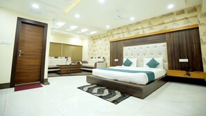 A modern bedroom with a large bed, a sofa, and a wooden headboard. - Hotel Jatashankar Palace (Chhatarpur)