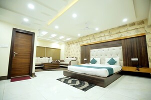 A modern bedroom with a large bed, a sofa, and a wooden headboard.