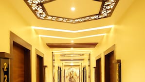 A hotel hallway with a geometric ceiling design, numbered doors, and a polished floor. - Hotel Jatashankar Palace (Chhatarpur)