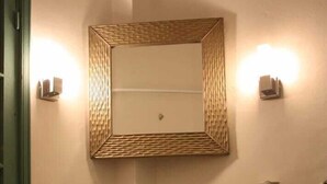 A bathroom with a large vessel sink, a mirror with a woven frame, and two wall-mounted lights. - Ryad Dar al Maknassia (Meknes)