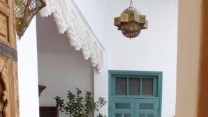 A traditional entrance with a teal door, a potted plant, and a hanging lantern. - Ryad Dar al Maknassia (Meknes)