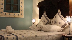 A bedroom with a bed, a nightstand, a wall-mounted lamp, and a decorative ceiling light. - Ryad Dar al Maknassia (Meknes)