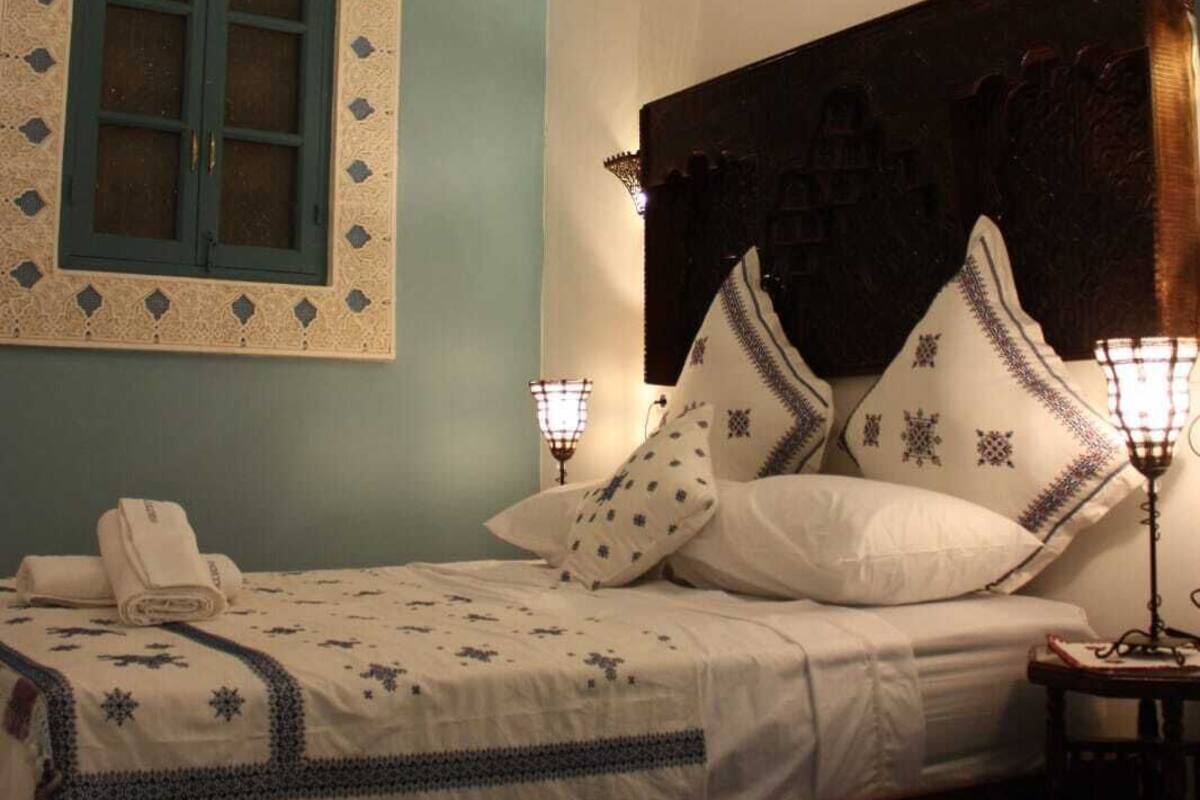 A bedroom with a bed, a nightstand, a wall-mounted lamp, and a decorative ceiling light.