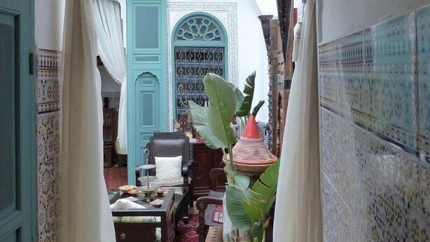 A narrow corridor with a traditional Moroccan door, a wooden bench, and potted plants. - Ryad Dar al Maknassia (Meknes)