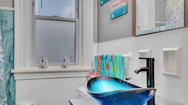 A bathroom with a white sink, a blue vessel sink, a window with blinds, and a towel rack with colorful towels. - Float away into serenity in our beautiful home (Rochester)